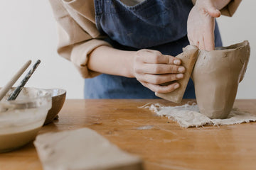 Person working with clay on a pottery wheel in a workshop setting (photo by cottonbro studio).